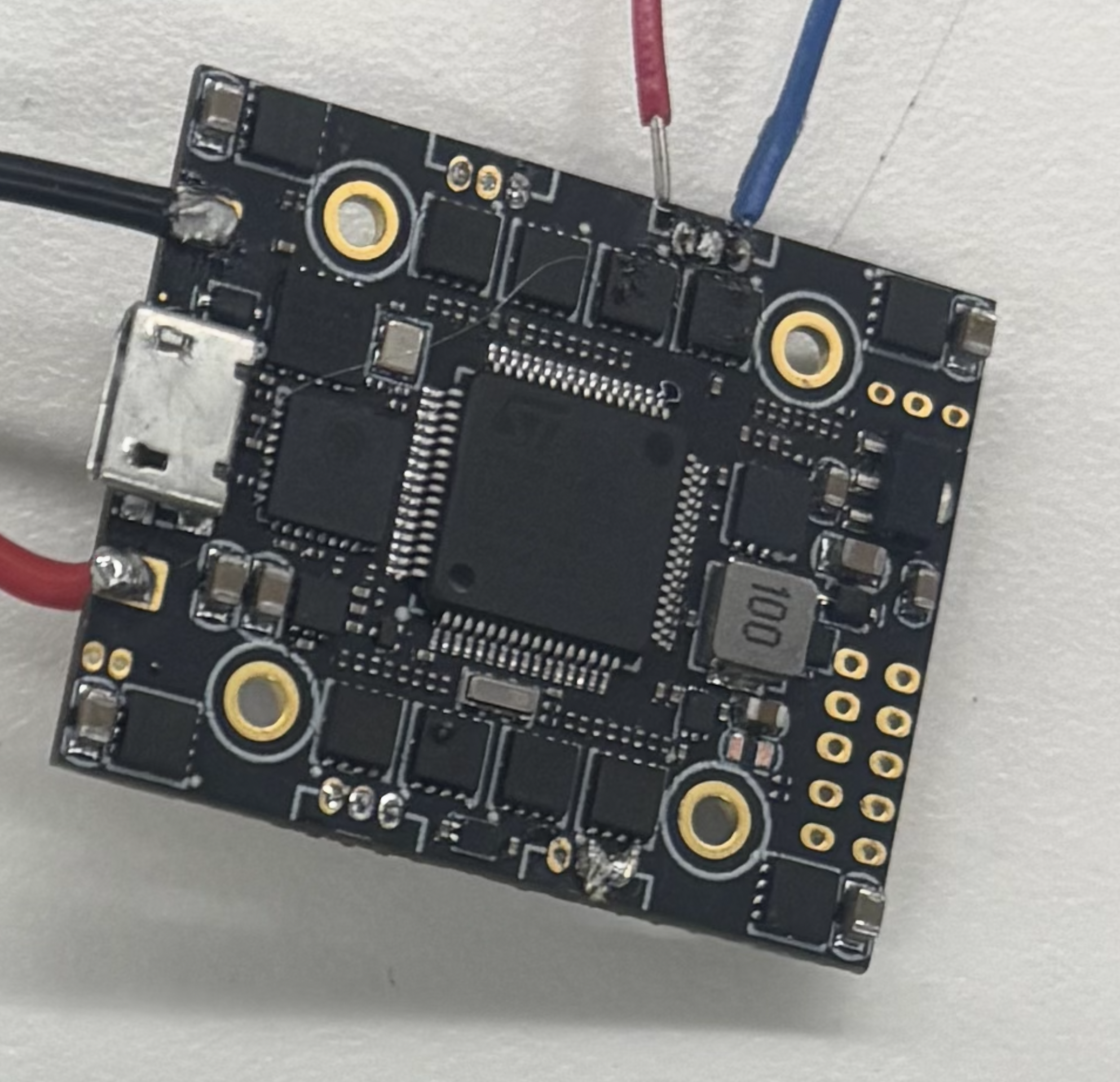 Close-up of the tiny solder pads on the AIO flight controller